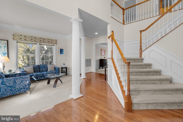 stairs featuring decorative columns, visible vents, wood finished floors, and crown molding