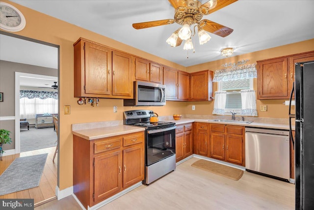 kitchen with light countertops, brown cabinets, appliances with stainless steel finishes, and a sink