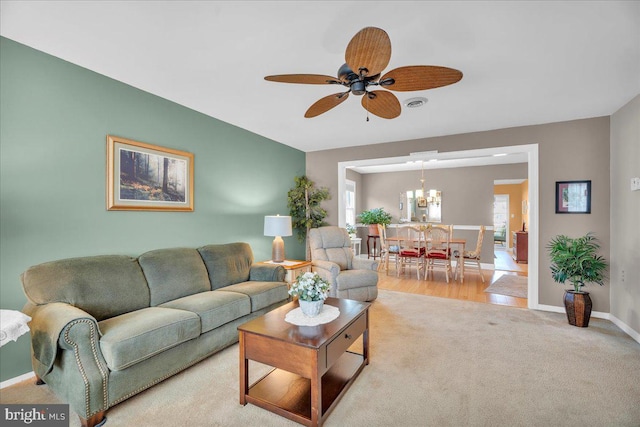 living room with visible vents, light colored carpet, a ceiling fan, and baseboards