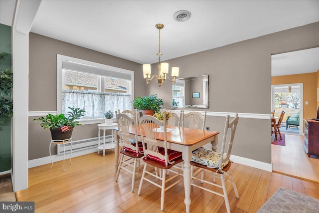 dining space with visible vents, baseboards, hardwood / wood-style flooring, a notable chandelier, and a baseboard radiator