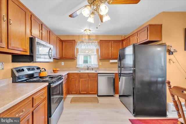 kitchen with light wood-type flooring, brown cabinets, a sink, stainless steel appliances, and light countertops