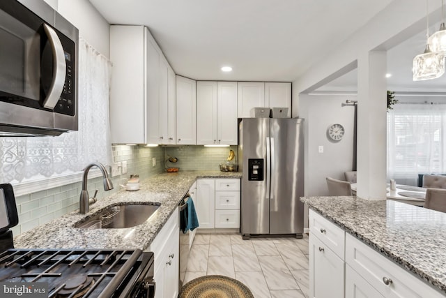 kitchen featuring tasteful backsplash, appliances with stainless steel finishes, marble finish floor, white cabinetry, and a sink