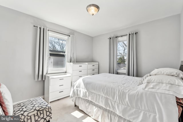 bedroom featuring baseboards, multiple windows, and light colored carpet