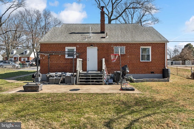 back of property with brick siding, an outdoor living space with a fire pit, a shingled roof, a lawn, and crawl space