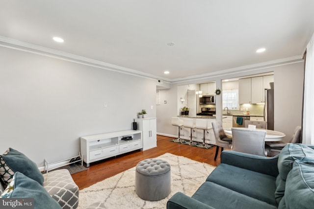 living area featuring recessed lighting, crown molding, baseboards, and wood finished floors