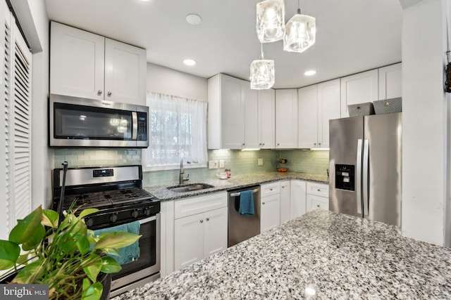 kitchen featuring backsplash, appliances with stainless steel finishes, white cabinets, and a sink