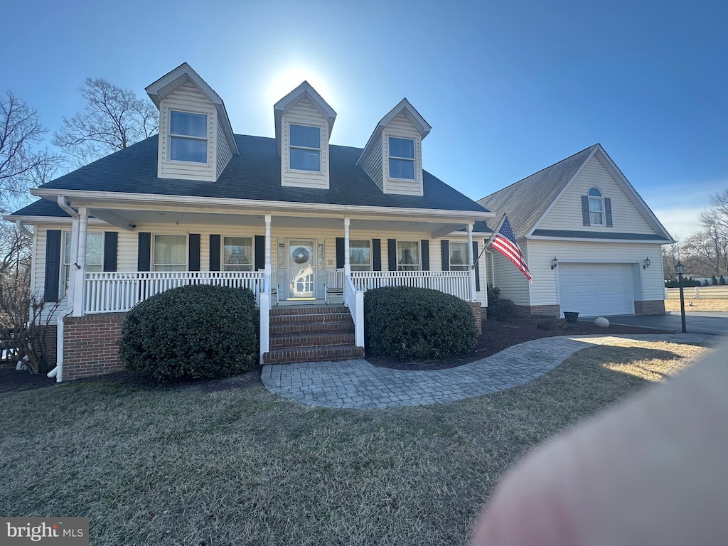 new england style home with an outbuilding, driveway, a porch, a front yard, and a garage