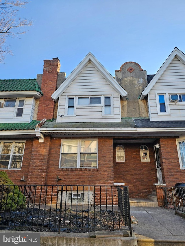 view of front of house with a fenced front yard, brick siding, and a shingled roof