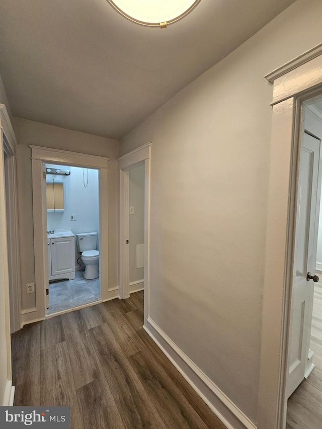 hallway featuring baseboards and dark wood-style flooring