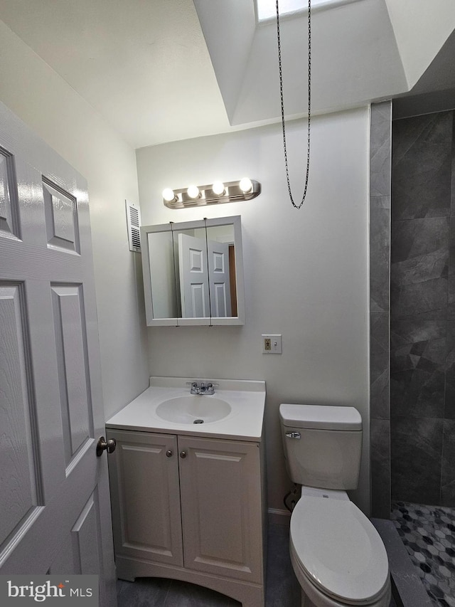 full bath featuring a tile shower, visible vents, toilet, and vanity