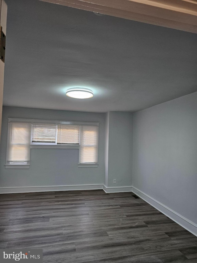 empty room with dark wood-style floors and baseboards