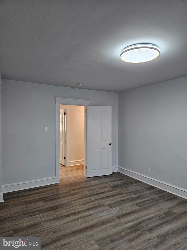 spare room with dark wood-type flooring and baseboards