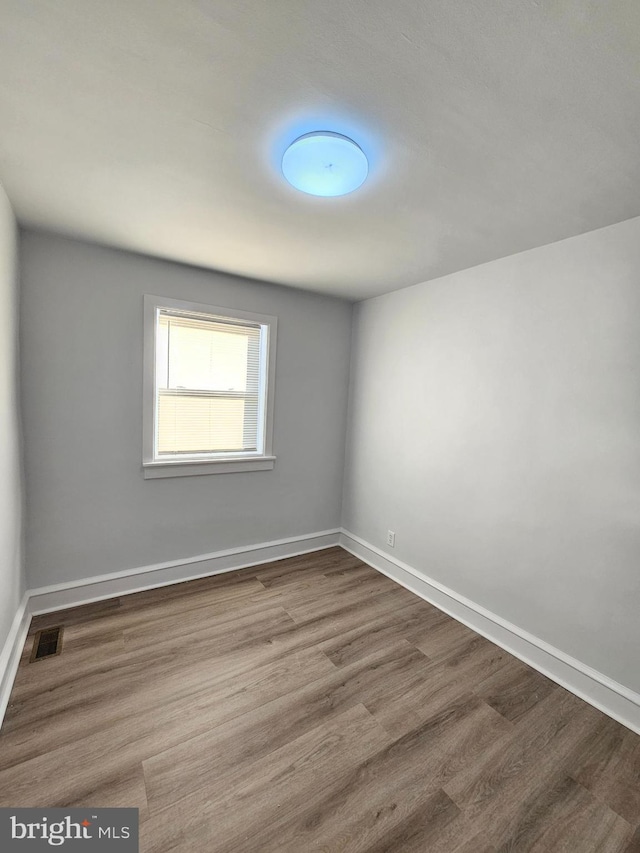 empty room featuring visible vents, baseboards, and wood finished floors