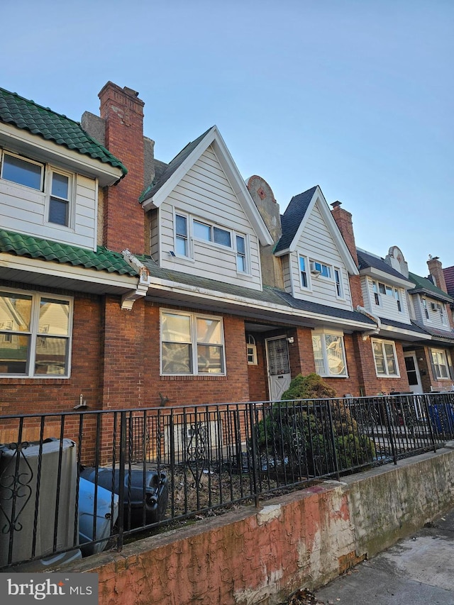 townhome / multi-family property with brick siding, a chimney, and fence