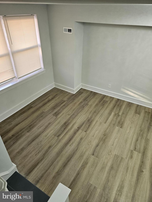 unfurnished room featuring wood finished floors, visible vents, and baseboards