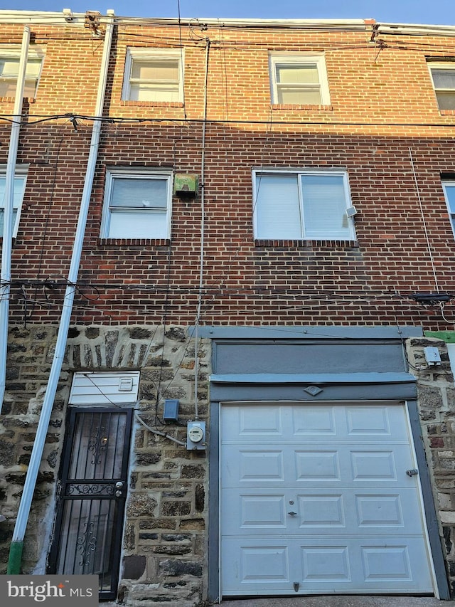 exterior space featuring brick siding, stone siding, and a garage