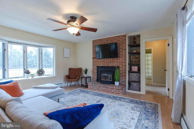 living area featuring a baseboard heating unit, wood finished floors, baseboards, and ceiling fan