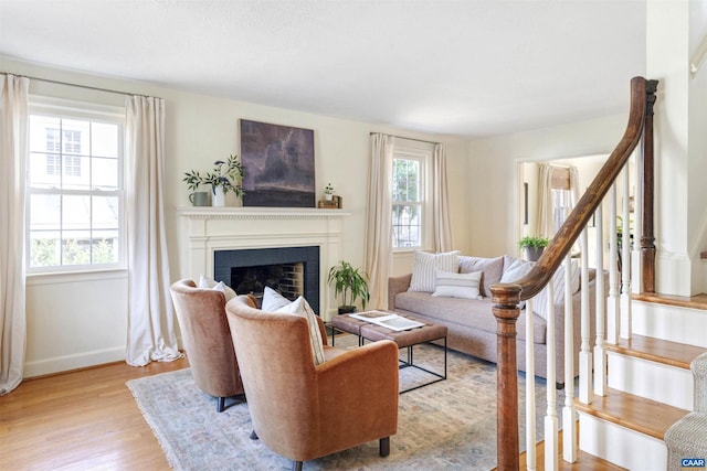 living room featuring stairs, wood finished floors, a fireplace, and baseboards