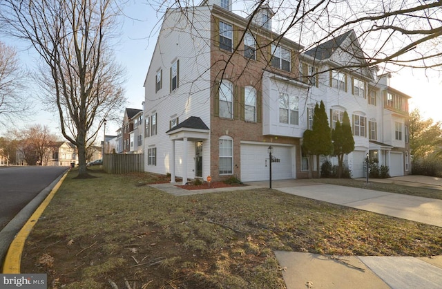 multi unit property featuring a garage, brick siding, a residential view, and driveway