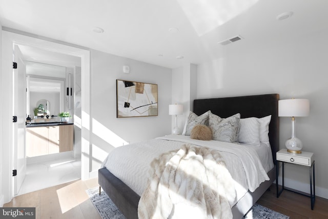 bedroom with visible vents, baseboards, and wood finished floors