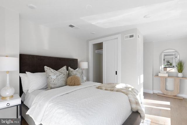 bedroom with visible vents, baseboards, and wood finished floors