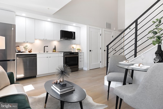 living area with stairs, recessed lighting, light wood-style floors, and visible vents