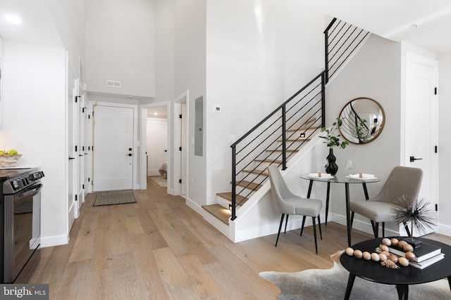 entryway featuring a high ceiling, light wood-style floors, visible vents, and baseboards