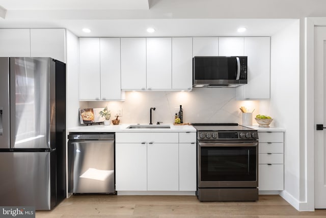 kitchen with a sink, stainless steel appliances, white cabinets, and light countertops