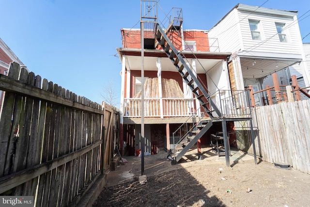 rear view of house featuring stairway and a fenced backyard