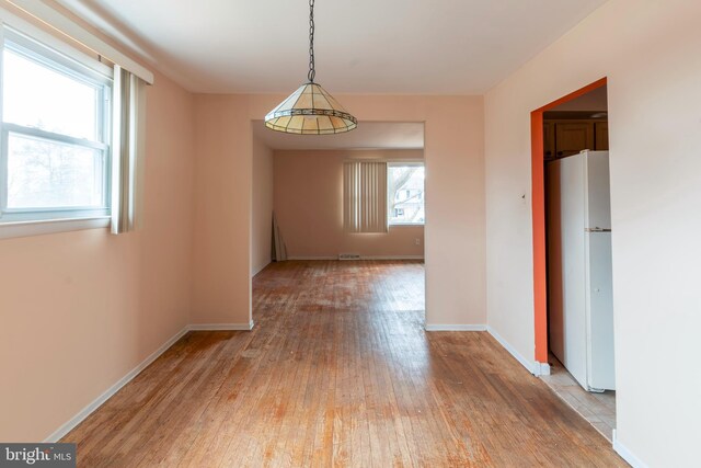 unfurnished dining area featuring baseboards and light wood-style flooring