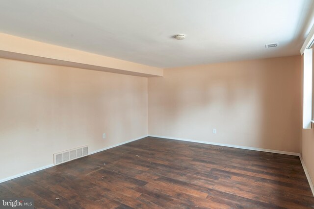 empty room with baseboards, visible vents, and dark wood-style flooring