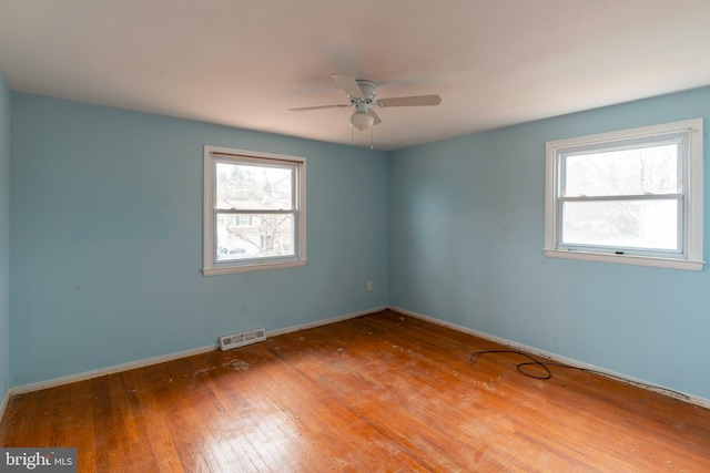 spare room featuring visible vents, a ceiling fan, baseboards, and hardwood / wood-style flooring