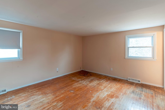 spare room with light wood-type flooring, visible vents, and baseboards