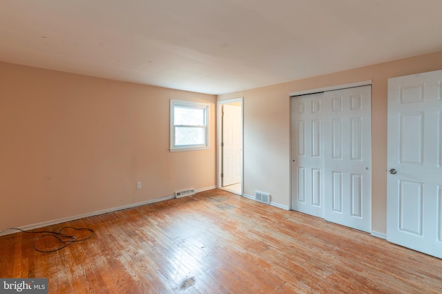 unfurnished bedroom with a closet, visible vents, light wood-style flooring, and baseboards