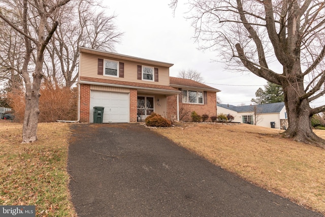 view of front of home featuring brick siding, driveway, a front lawn, and a garage