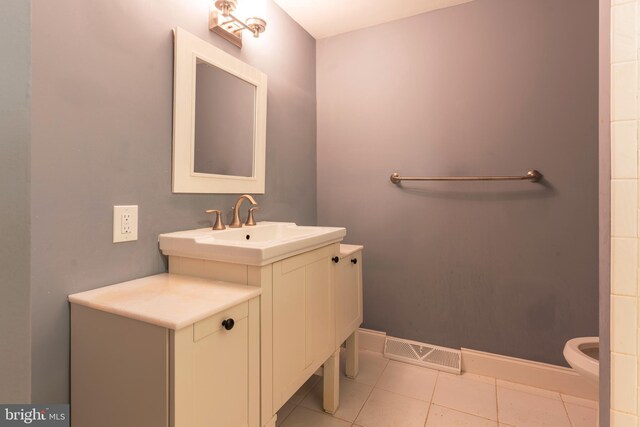 bathroom featuring visible vents, baseboards, toilet, tile patterned floors, and a sink