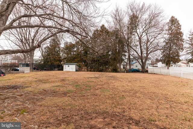 view of yard featuring an outbuilding, a storage shed, and fence