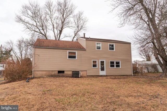 back of house with central air condition unit and a lawn