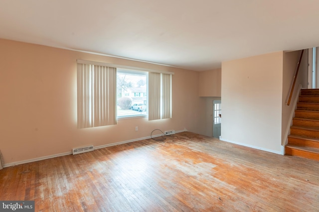 unfurnished living room featuring visible vents, baseboards, hardwood / wood-style floors, and stairway