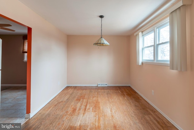 spare room featuring visible vents, ceiling fan, baseboards, and wood-type flooring