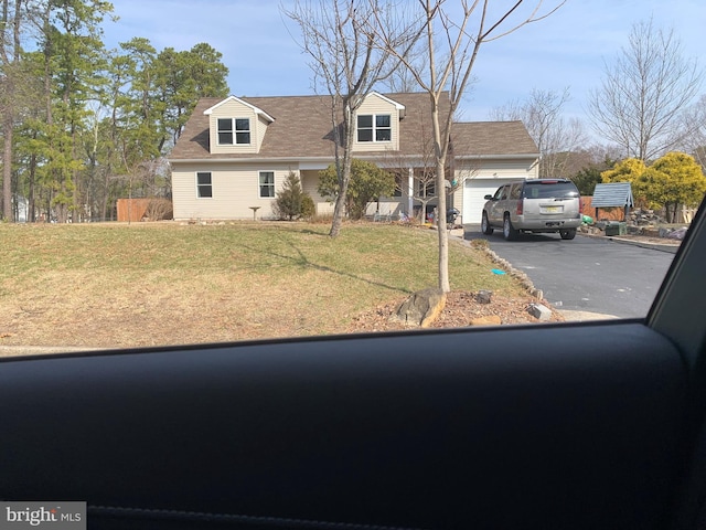 cape cod-style house with a front yard, an attached garage, and driveway