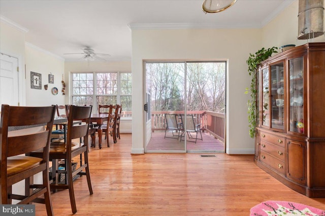 dining space with visible vents, ornamental molding, a ceiling fan, light wood finished floors, and baseboards