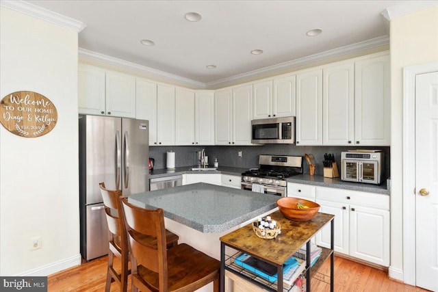 kitchen with light wood-type flooring, stainless steel appliances, dark countertops, and backsplash