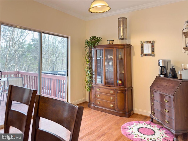 dining room with light wood-type flooring, baseboards, and ornamental molding