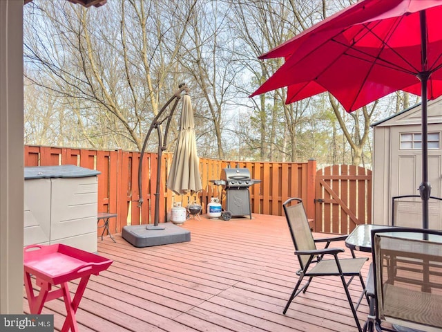 wooden terrace featuring an outbuilding, a storage shed, and a gate