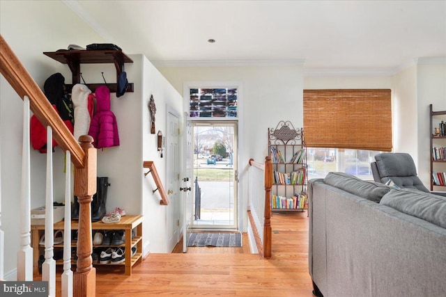 foyer with stairway, light wood-style floors, and ornamental molding