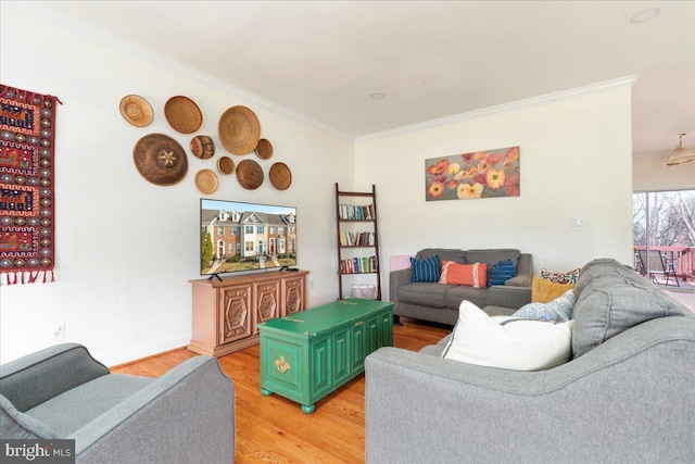 living area featuring baseboards, light wood-style flooring, and crown molding