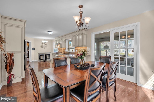 dining space with baseboards, wood finished floors, and a chandelier