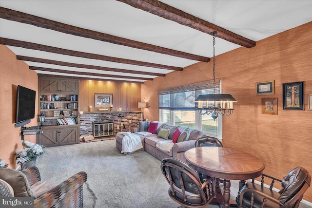 living area featuring beam ceiling, a notable chandelier, carpet flooring, and a fireplace