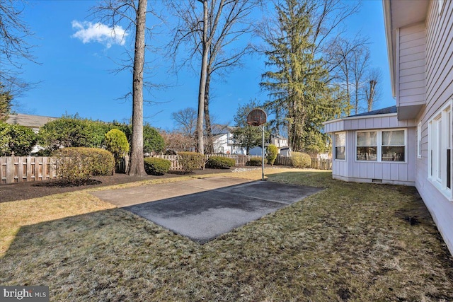 view of yard with basketball hoop and fence